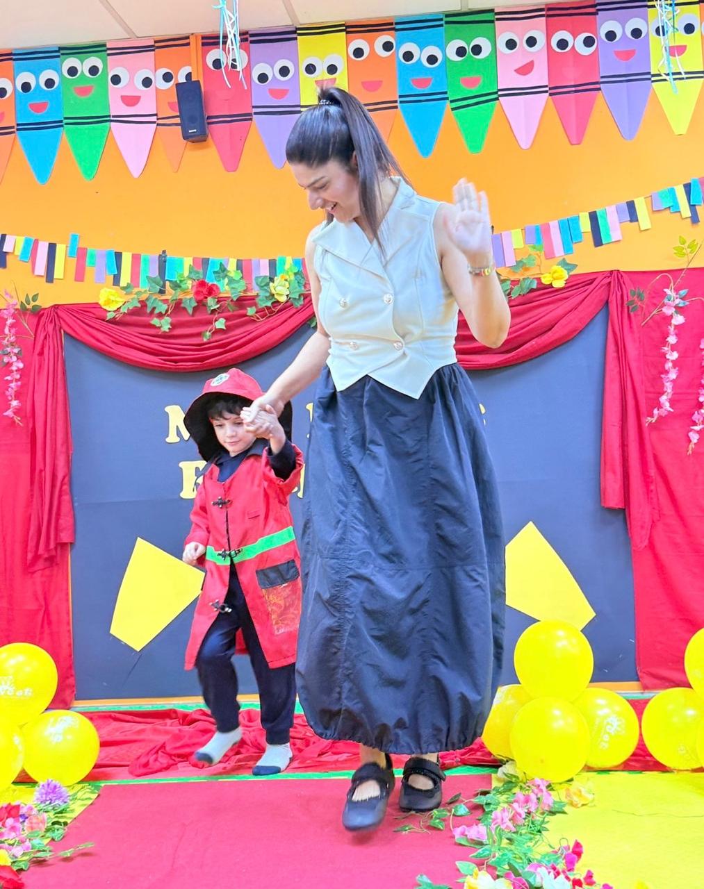A little firefighter walking hand in hand with his educator on stage