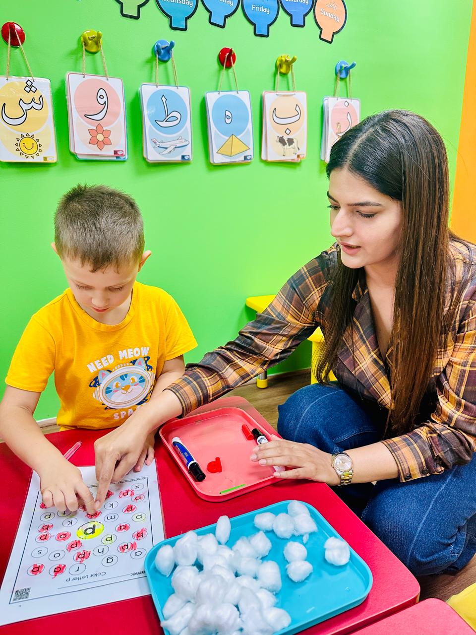 An educator guiding a child through a letter P phonics activity