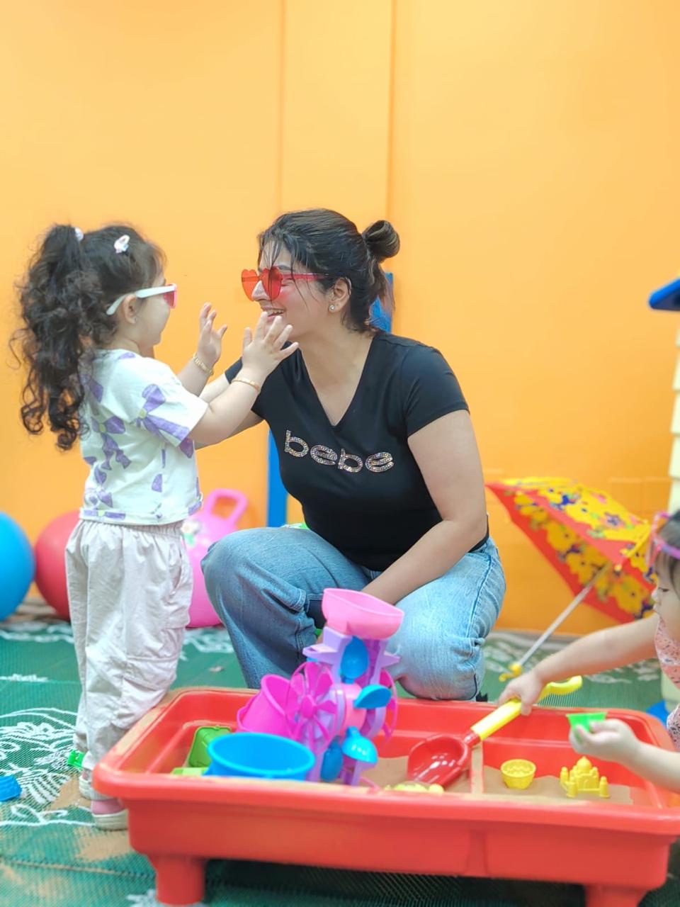 A toddler laughing with her educator during sensory play