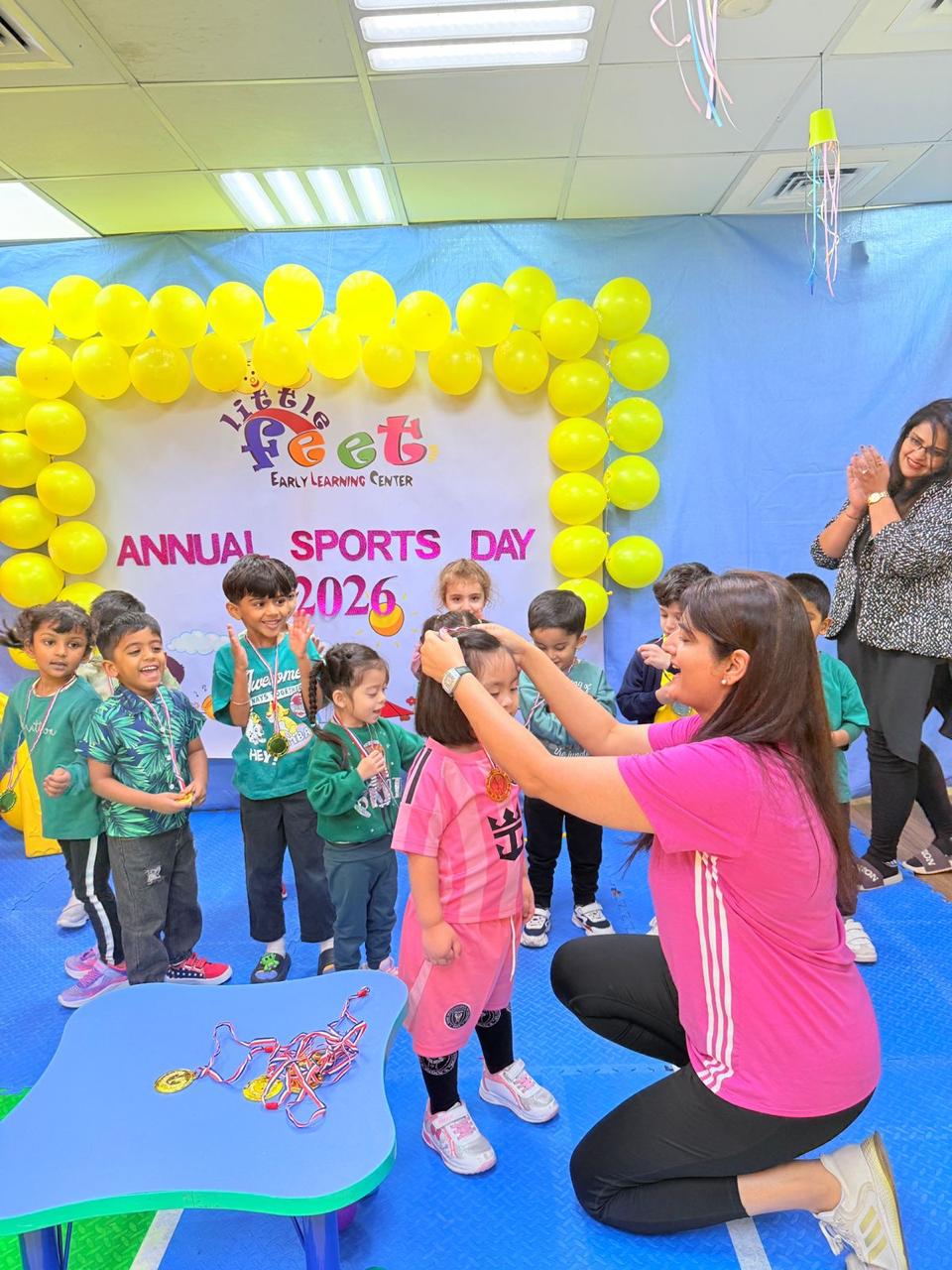 An educator placing a medal on a child while classmates cheer at Annual Sports Day 2026