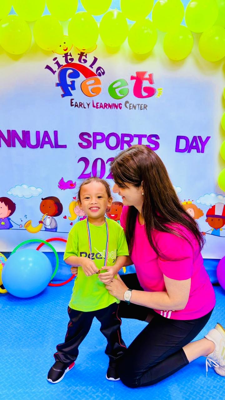 A proud boy showing his Sports Day medal with his educator