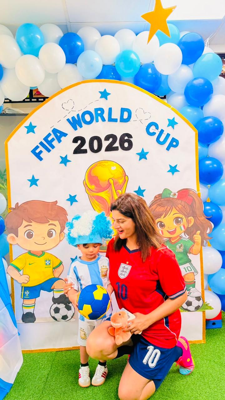 A child in an Argentina kit and his educator in front of the FIFA World Cup 2026 backdrop